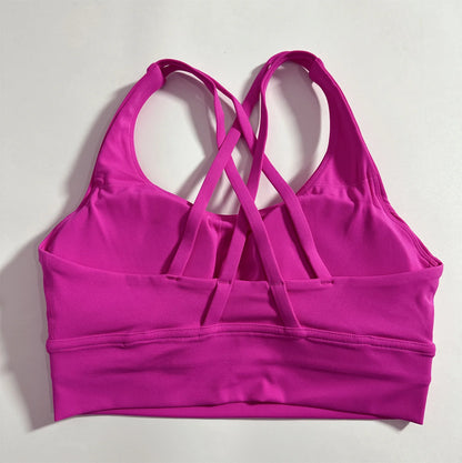 Women's cross-back padded sports bra in fuchsia pink with crisscross straps and padded cups.