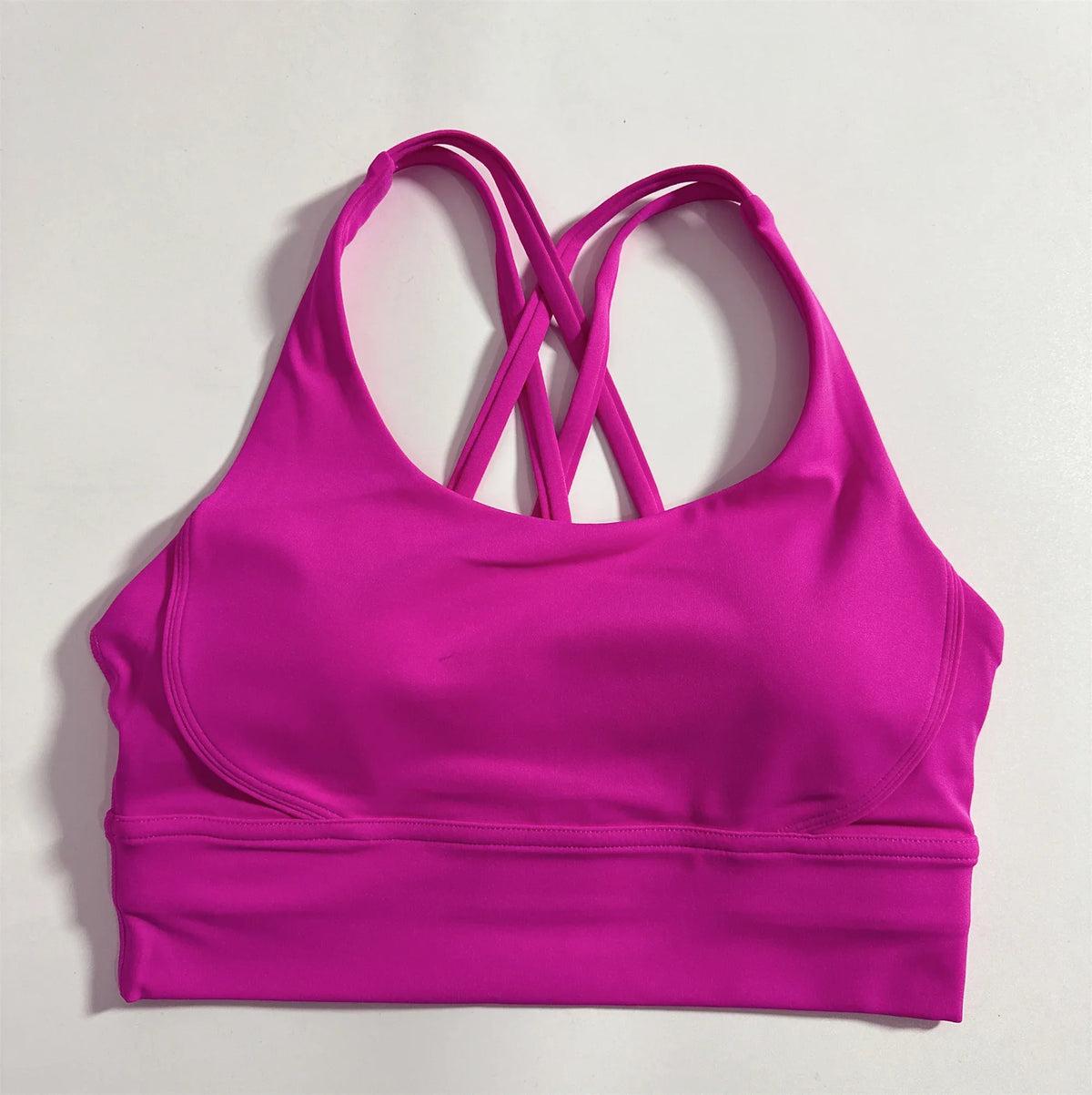 Magenta padded sports bra with crisscross cross-back straps and wide elastic hem.