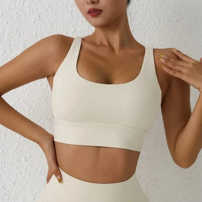 Cream padded cross-back sports bra with wide straps and curved underband
