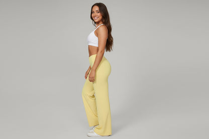 Yellow flared pants worn by a person on a gray background