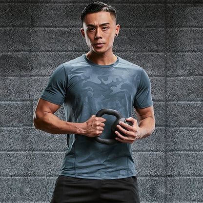Man holding a kettlebell against a gray brick wall