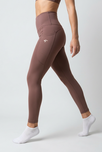 A model wearing high-waisted athletic leggings in a dusty mauve-brown color, shown from the waist down against a light gray studio background.