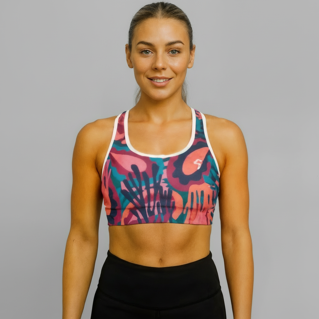 Woman wearing a colorful sports bra and black pants against a beige background