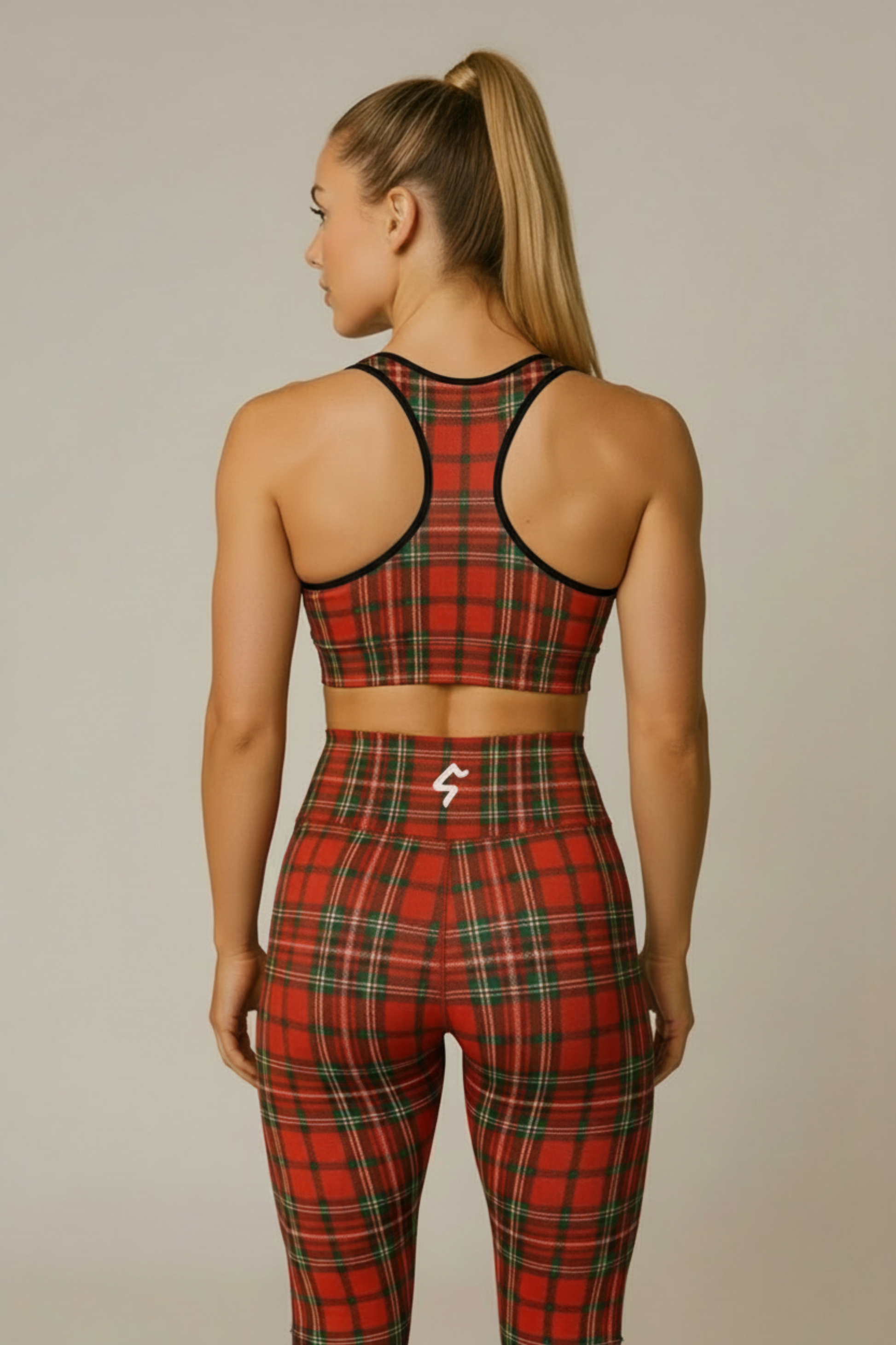 Person wearing a red plaid sports bra and leggings set on a beige background