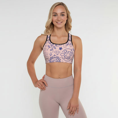 A woman wearing a pink and black multicolored sports bra with a graphic design, posing with a smile.