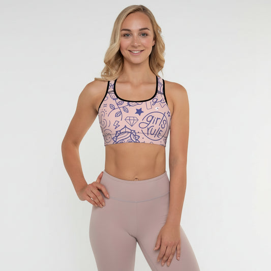 A woman wearing a pink and black multicolored sports bra with a graphic design, posing with a smile.
