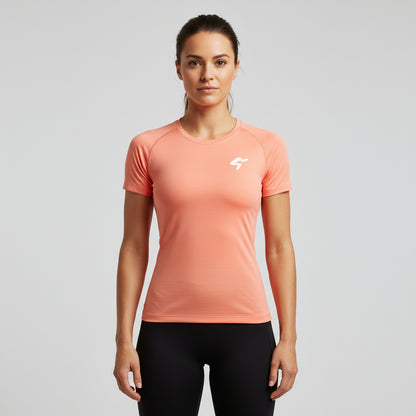 Woman wearing a peach-colored athletic shirt with a logo on a gray background