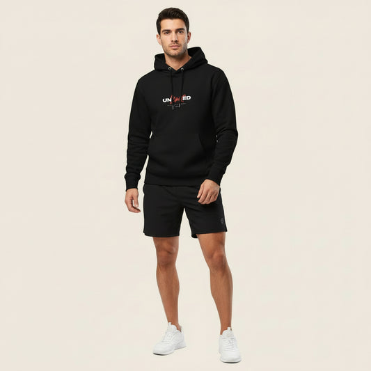 A man wearing a black The Gymbum UK Unlimited Men's eco hoodie with a front pouch pocket, set-in sleeves, and a double-layered hood.