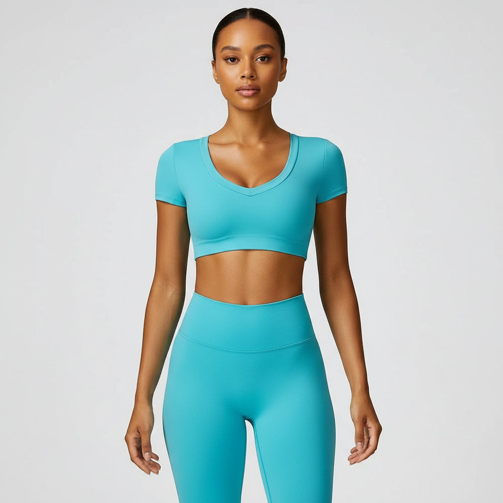A woman wearing a blue, short-sleeved crop top yoga t-shirt and matching leggings.