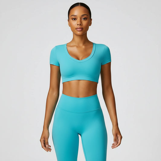 A woman wearing a blue, short-sleeved crop top yoga t-shirt and matching leggings.