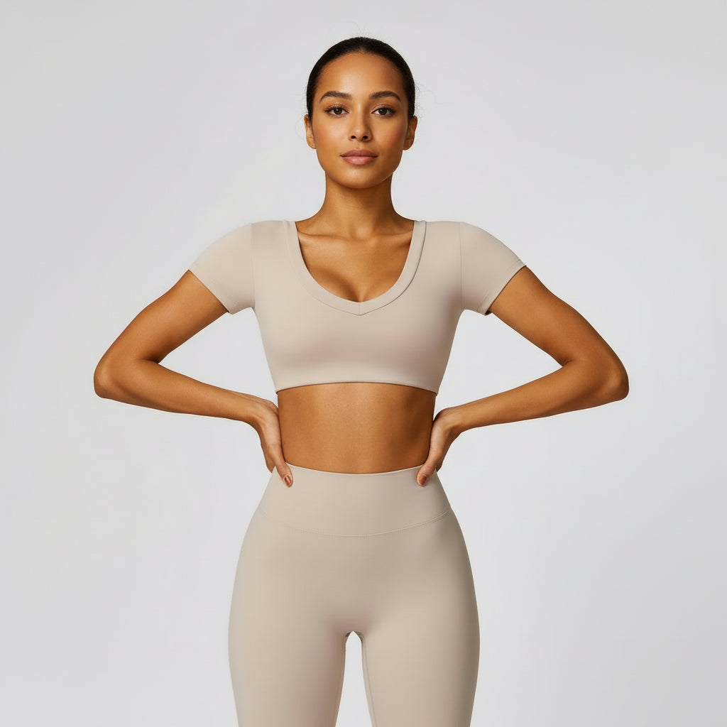 Person wearing a beige athletic top and leggings on a light gray background