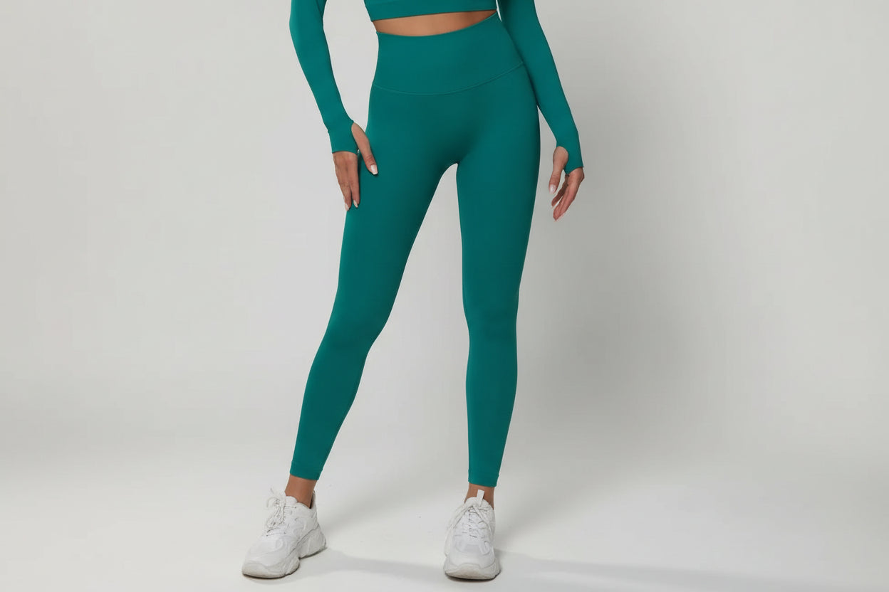 Person wearing teal athletic leggings and a matching top on a white background