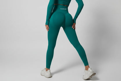 Person wearing teal athletic leggings and white sneakers against a dark background