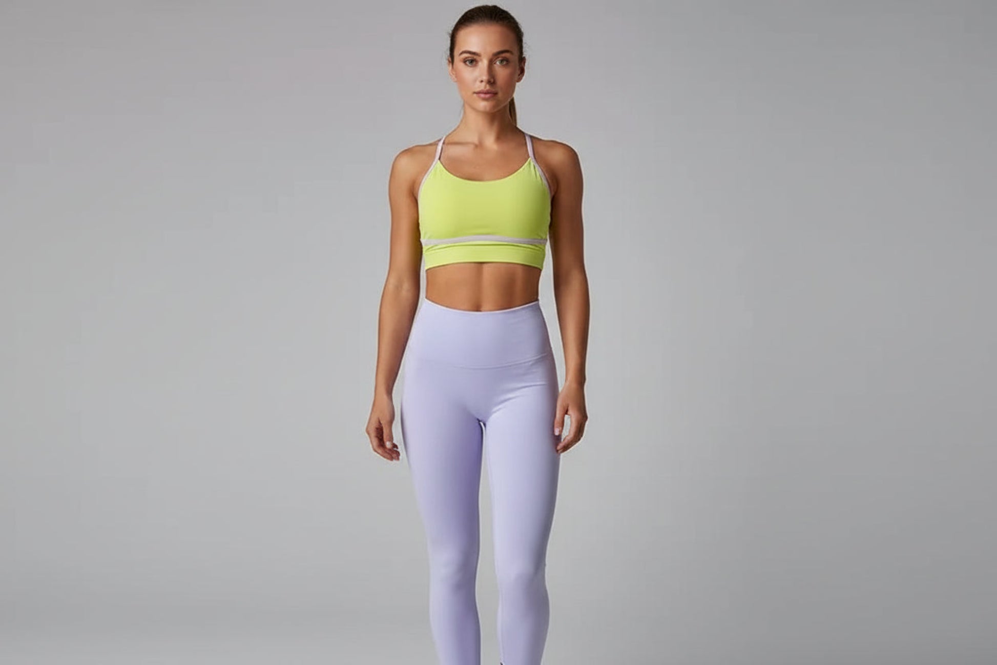 Yellow sports bra and lavender leggings on a gray background