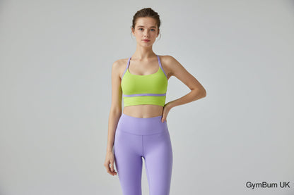 Woman in green sports bra and purple leggings sitting on a wooden floor.