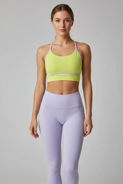 Yellow sports bra and purple leggings on a gray background