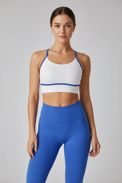 White sports bra with blue trim and matching leggings on a gray background