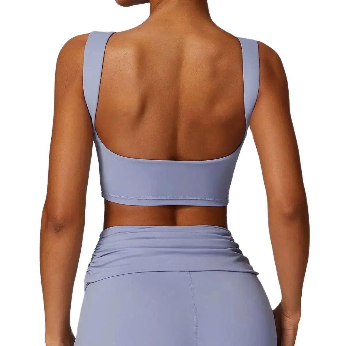 A gray tank top with wide shoulder straps and a low back, made of nylon fabric, on a model.