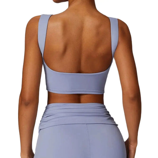 A gray tank top with wide shoulder straps and a low back, made of nylon fabric, on a model.