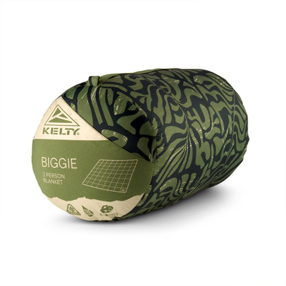 Rolled camping blanket with leaf-pattern cover and green and beige end label