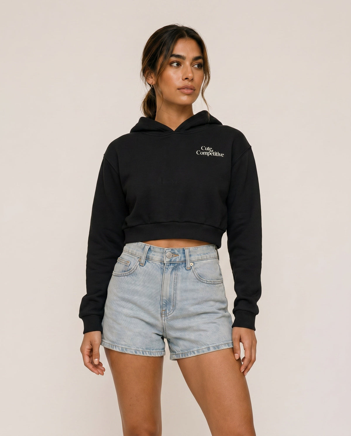 Black cropped hoodie with hood and small chest logo, front view.