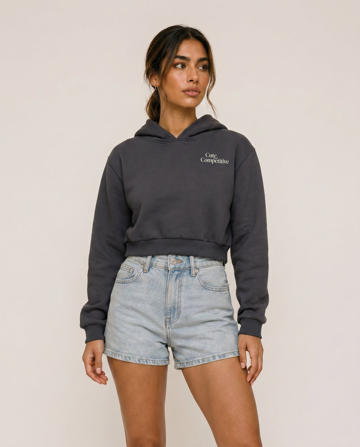 Charcoal gray cropped hoodie with hood and small chest logo, front view.