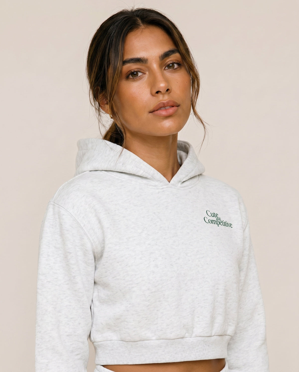 Light gray cropped hoodie with hood and small chest logo, close-up view.