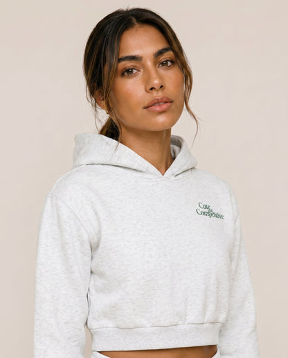 Light gray cropped hoodie with hood and small chest logo, close-up view.