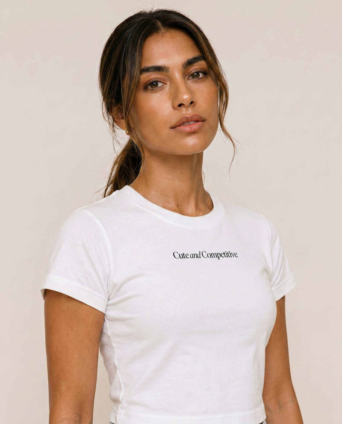 Cropped white crew-neck T-shirt with short sleeves; “Cute and Competitive” chest print