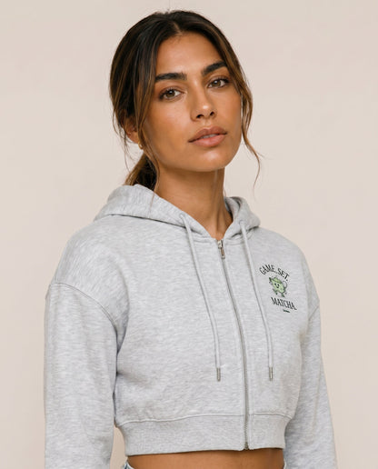 Light gray cropped zip hoodie with hood drawstrings and front logo print.