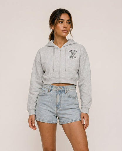 Light gray cropped zip hoodie with hood drawstrings and chest logo.