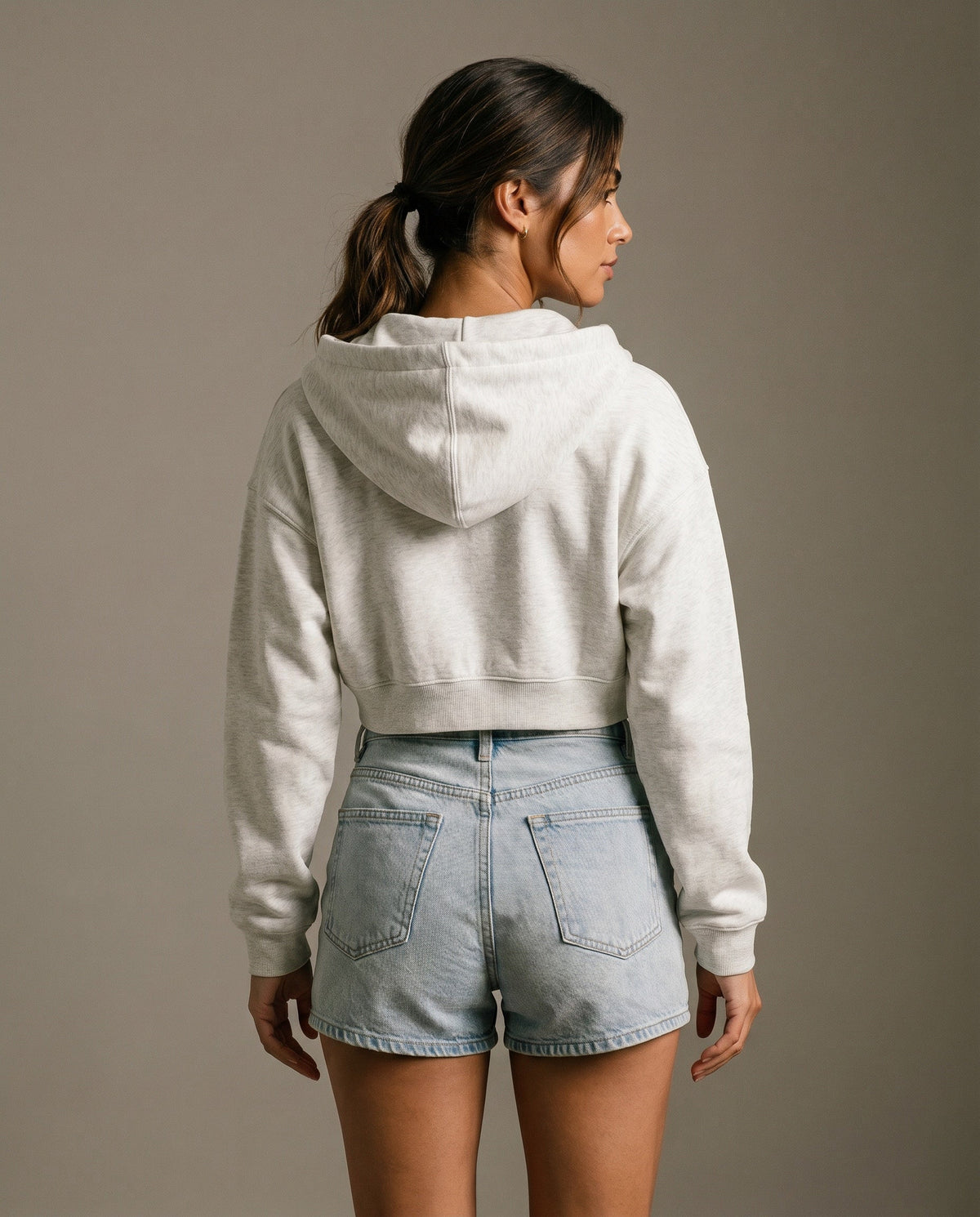 Back view of cropped zip hoodie in light gray with hood and drawstring