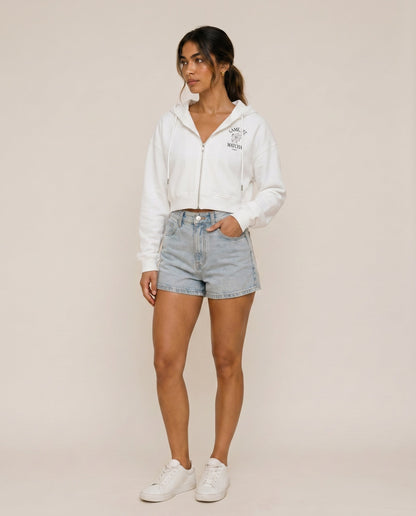 Cropped zip hoodie in white with hood and drawstring, worn with denim shorts