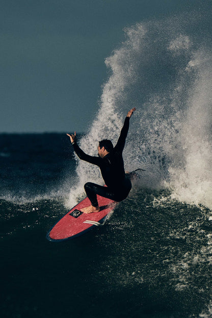 Black wetsuit steamer with chest zip, worn by surfer on surfboard