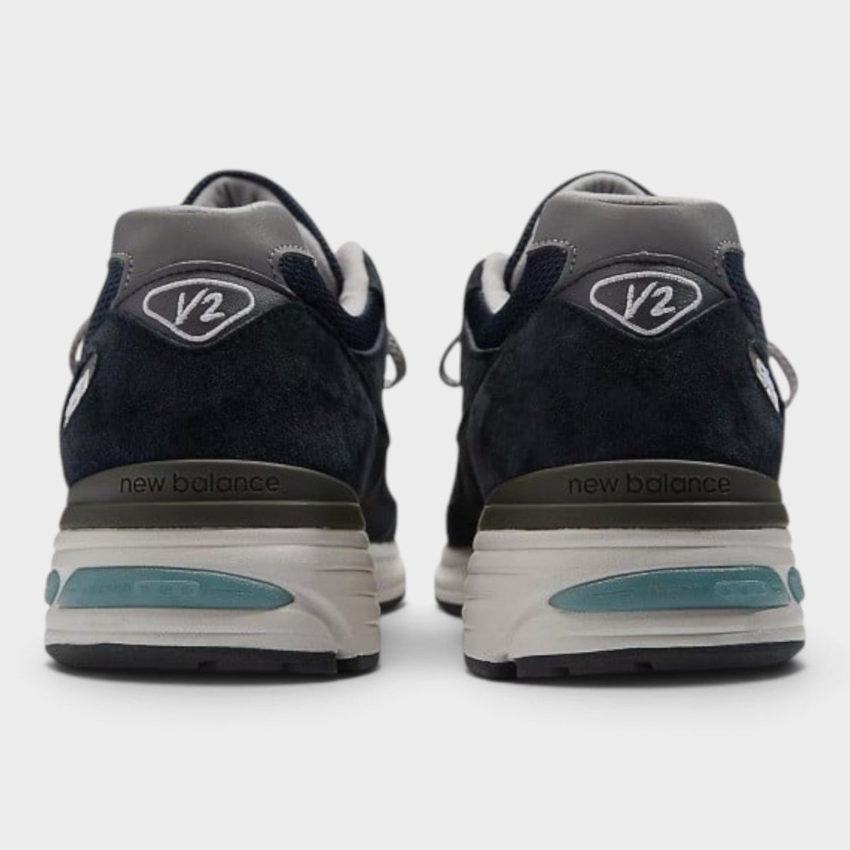 Dark navy New Balance 991v2 sneakers with heel tab, V2 branding, and teal stripe
