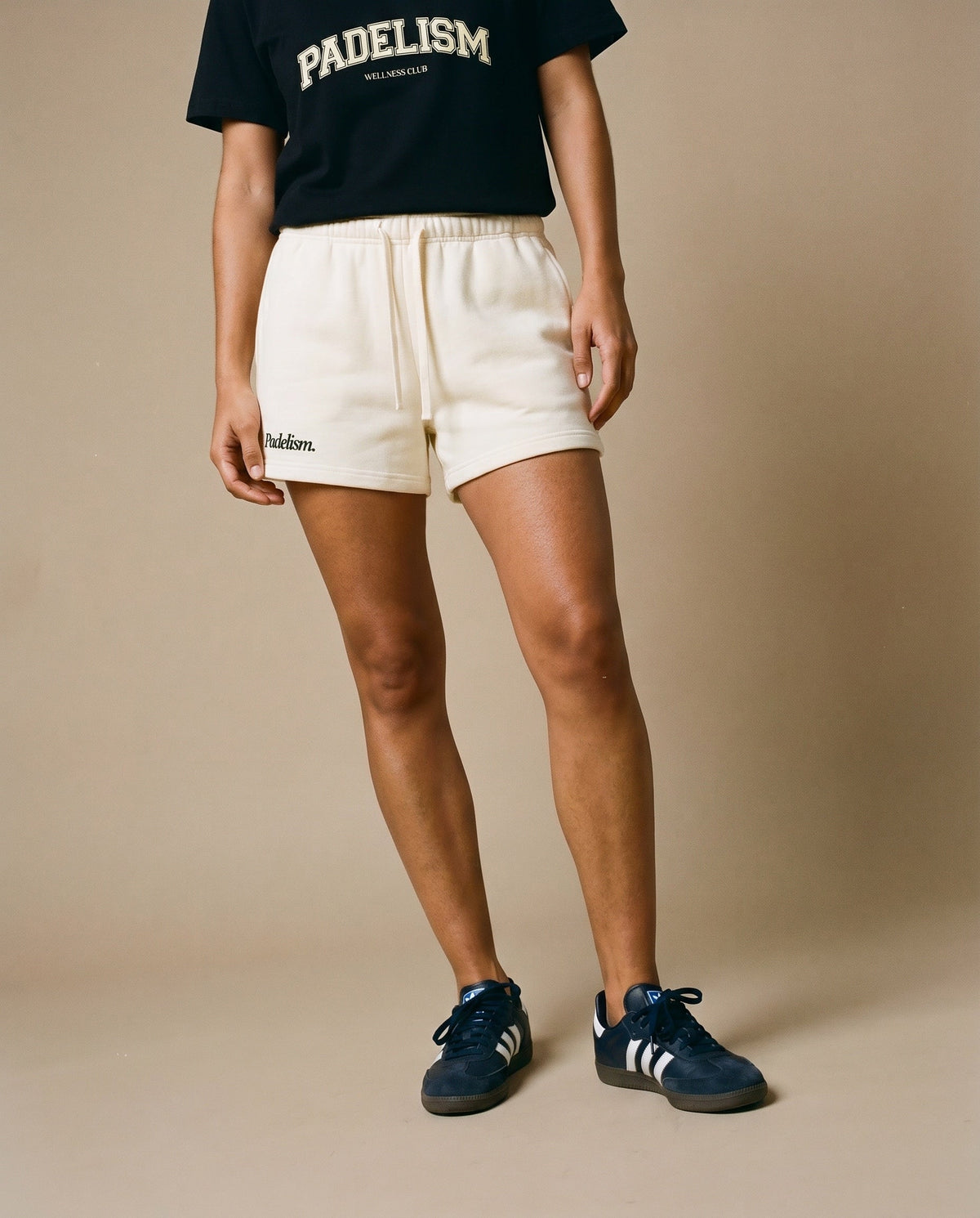 Cream drawstring shorts with elastic waist and embroidered logo on left leg