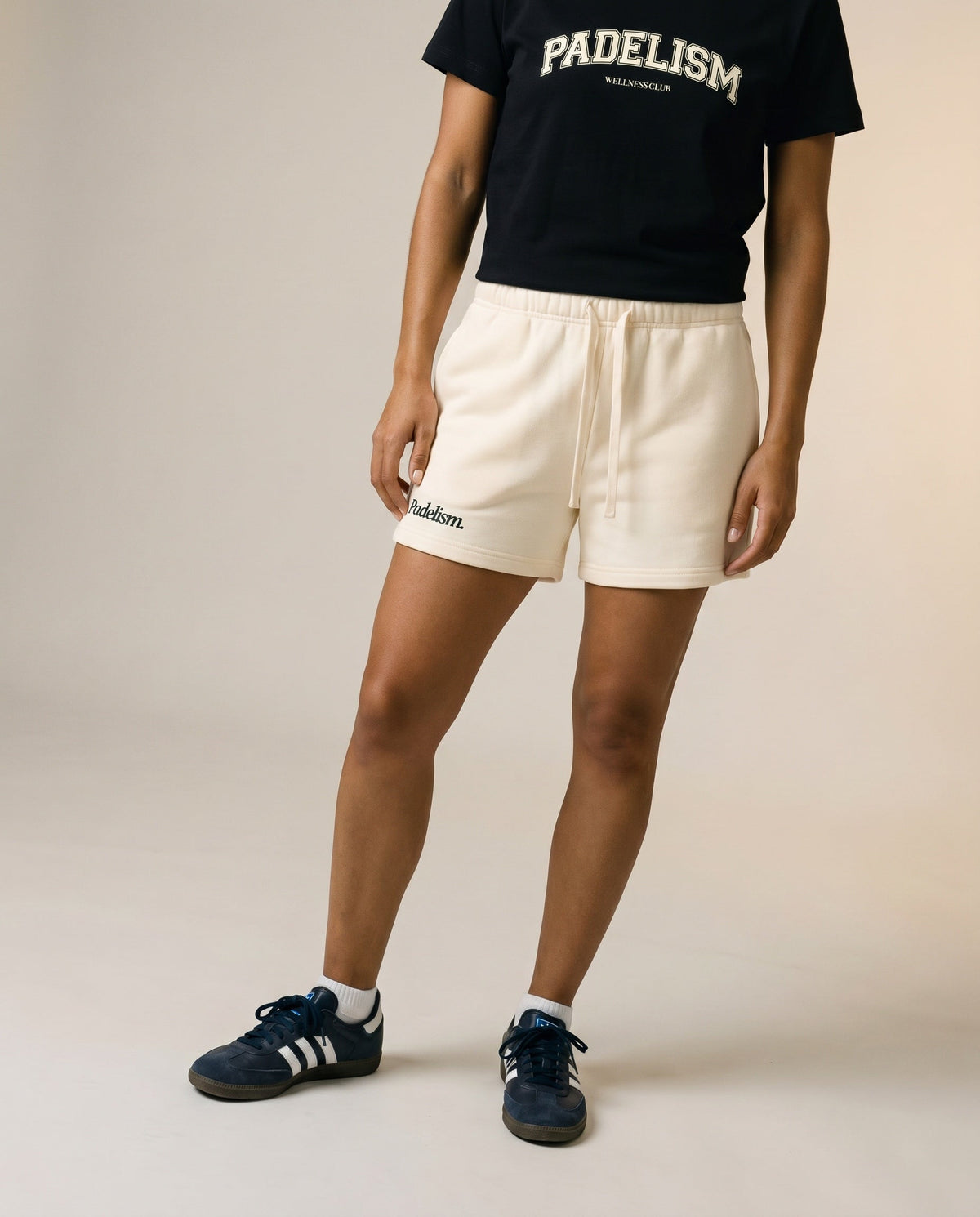 Cream core shorts with elastic waistband, drawstring, and logo detail on front