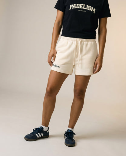 Cream core shorts with elastic waistband, drawstring, and logo detail on front