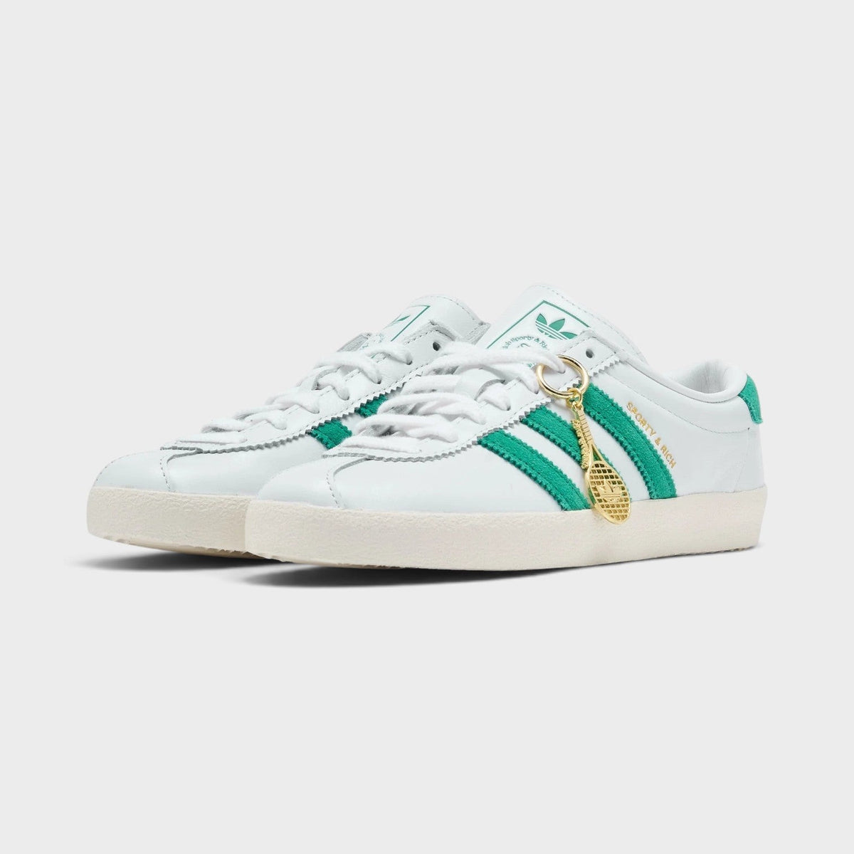 White low-top sneakers with green side stripes, lace-up front, beige outsole