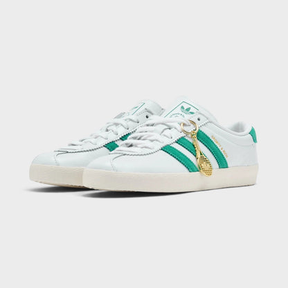 White low-top sneakers with green side stripes, lace-up front, beige outsole