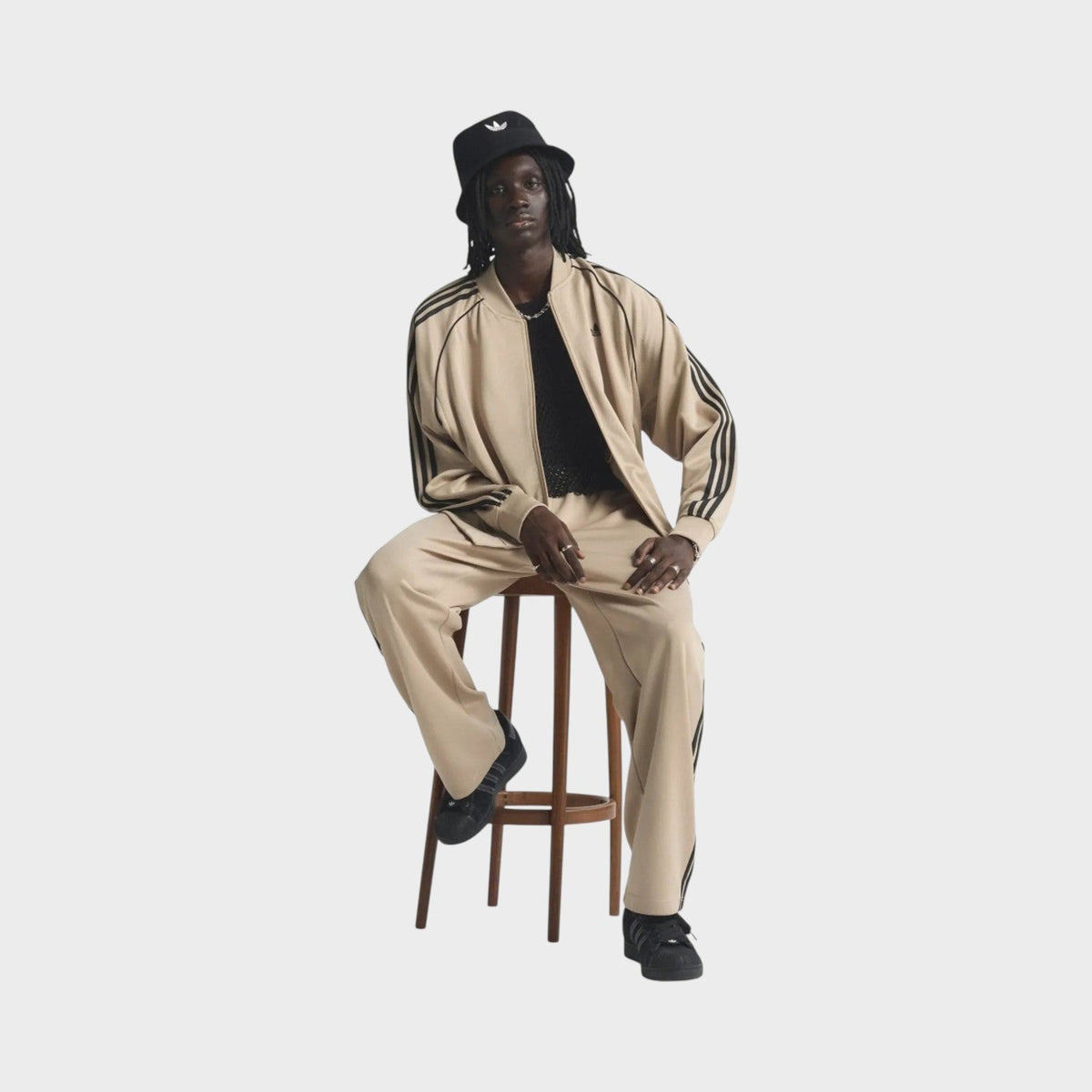 Beige adidas track jacket with zip front, black side stripes, and elastic cuffs