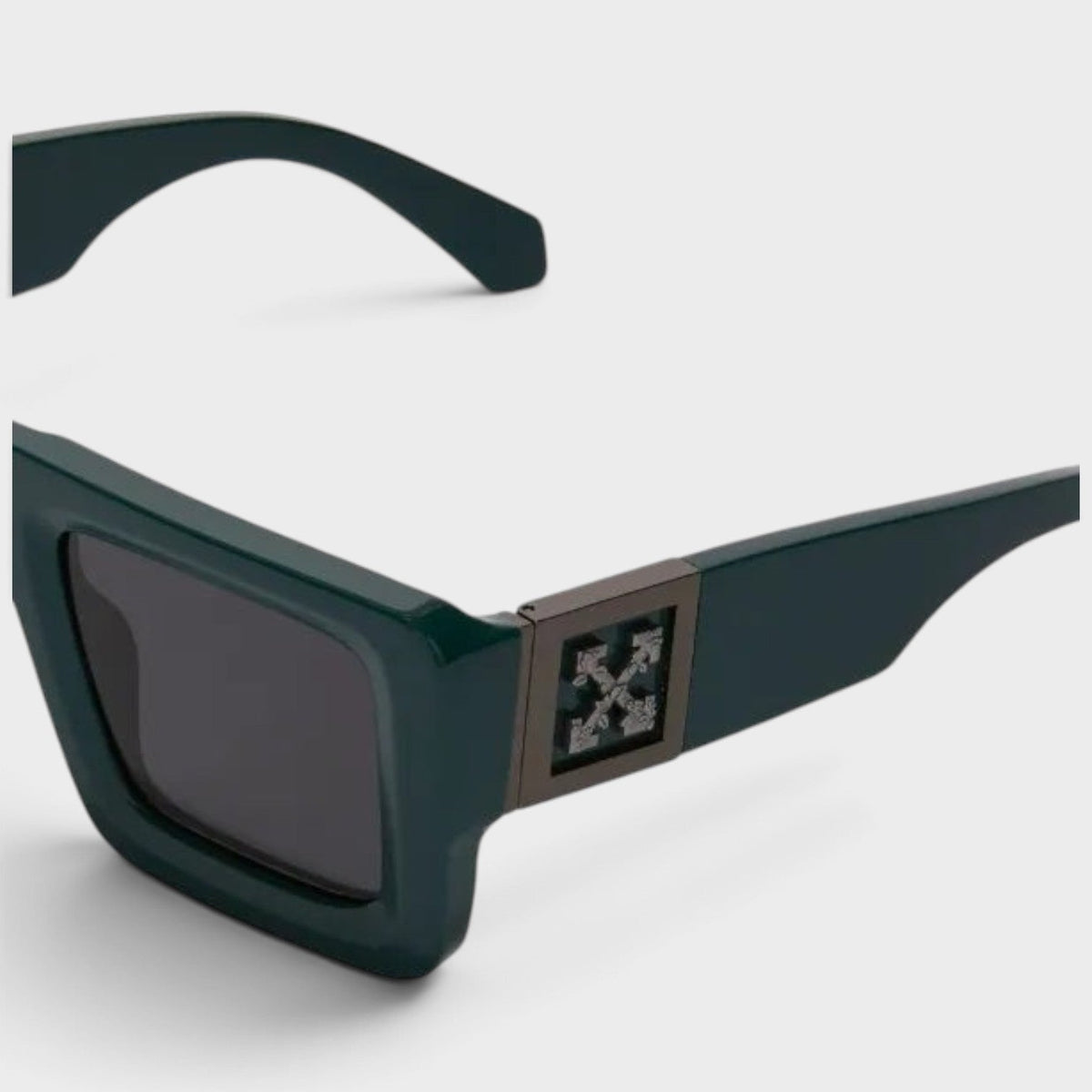 Green sunglasses close-up, square front with dark lens and decorative logo plate