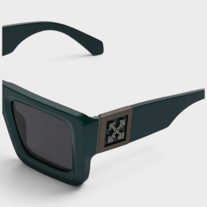 Green sunglasses close-up, square front with dark lens and decorative logo plate