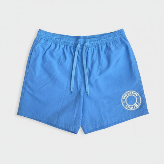 Periwinkle blue nylon swim shorts with logo patch on leg