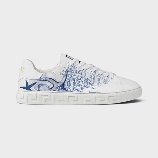 White low-top sneakers with blue Greca-style trim and graphic side embroidery