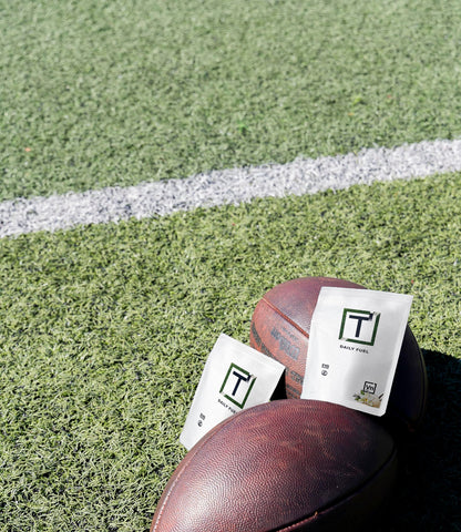 Protein powder pouch set on grass: dark brown pouch and white pouch with green T logo.