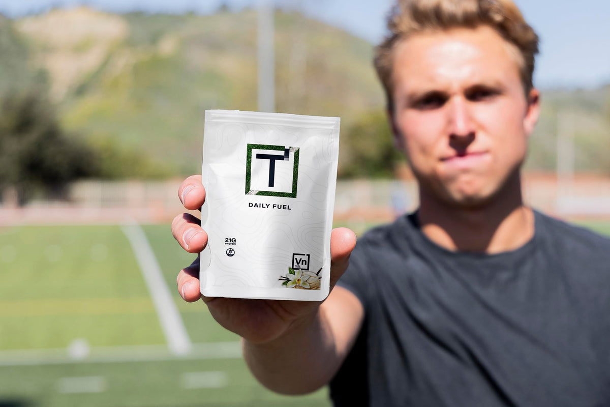 Daily Fuel protein powder pouch held in hand, white bag with green T logo.